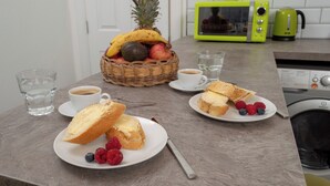 Ein Frühstücksbuffet mit Obstkorb, Kaffee und Waffeln auf einer Küchenarbeitsplatte.