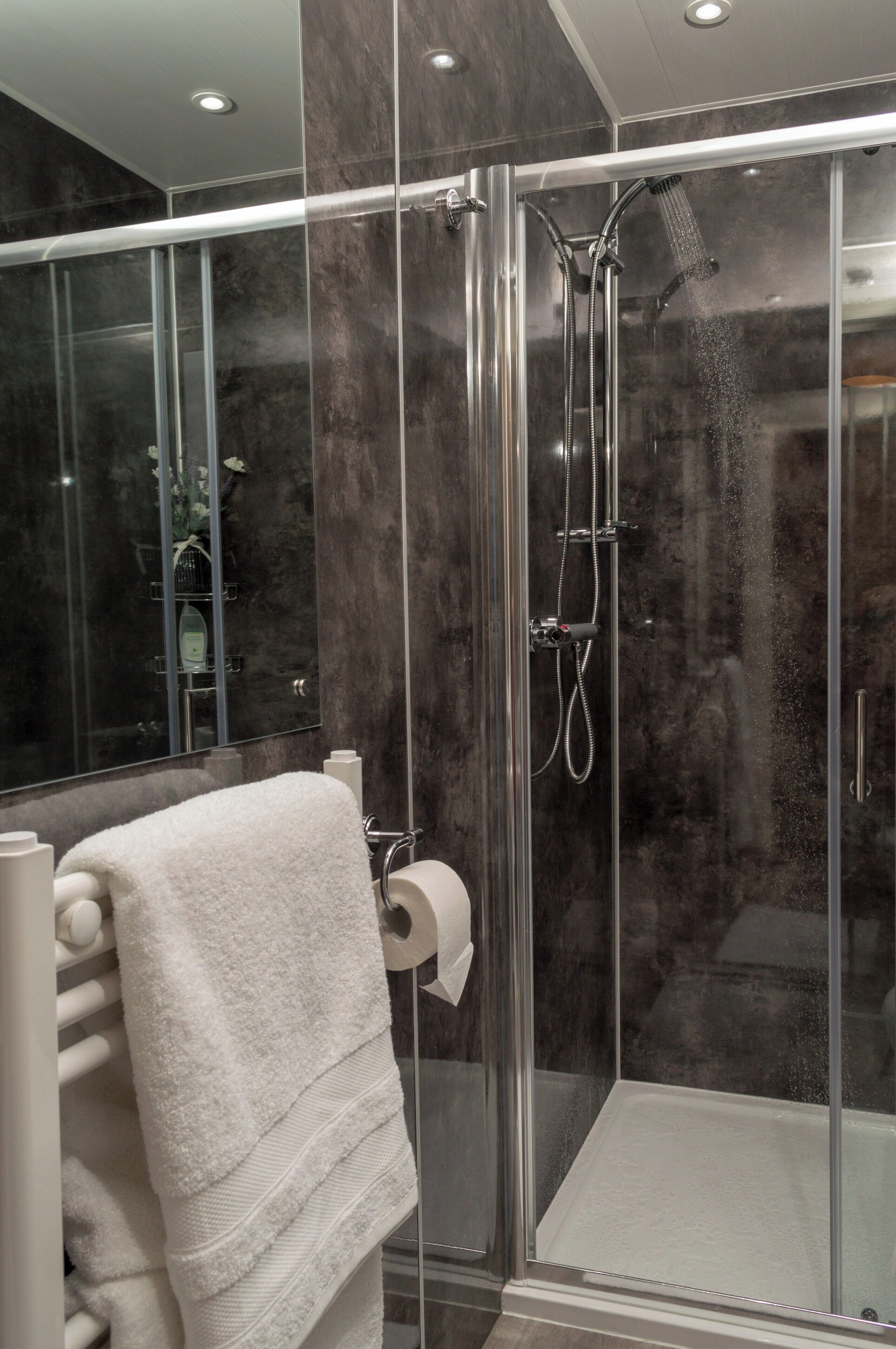 A modern bathroom with a glass-enclosed shower, a white towel, and a marble wall.