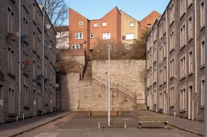 Une rue étroite en milieu urbain, avec un escalier central menant à un immeuble doté de nombreuses fenêtres.