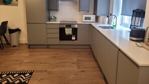 A modern kitchen with grey cabinets, a microwave, and a kettle. - Batterseaflat/sleeps6/refurbished/tv (London)