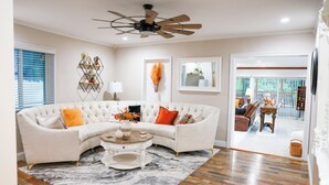 A living room with a sectional sofa, a ceiling fan, a coffee table, and a view into the dining area.