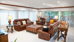 A spacious living room with leather sofas, a coffee table, and a dining table.
