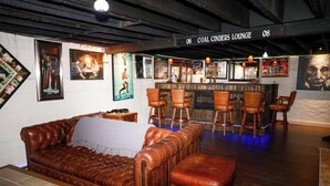 A lounge with a brown leather sofa, wooden bar stools, and a sign reading "COAL CINDERS LOUNGE".