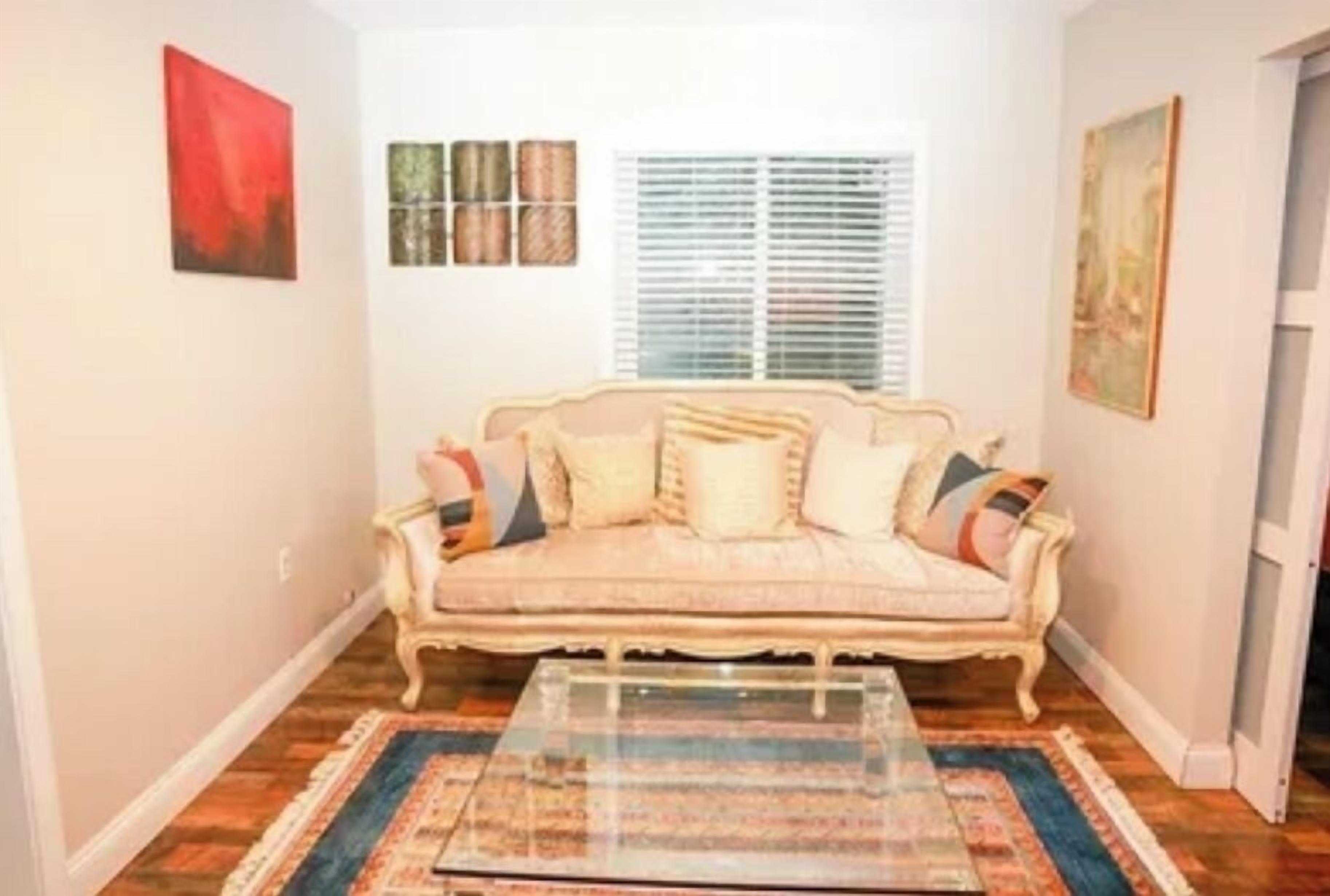 A living room with a sofa, a coffee table, and a window with blinds.