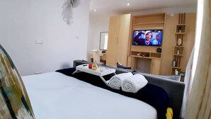 A hotel room with a bed, a TV, a desk, and a seating area. - Sunset Bliss Paradise in Lilongwe (Lilongwe)