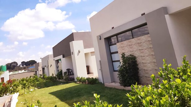 A modern building with a flat roof, large windows, and a well-maintained lawn with small plants. - Sunset Bliss Paradise in Lilongwe (Lilongwe)
