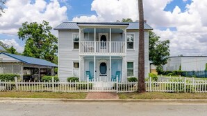 A two-story house with a balcony, a porch, and a white picket fence. - Historic Colonial Retreat in Downtown Brunswick (Brunswick)