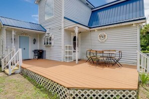 A two-story house with a wooden deck and a covered porch.