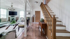 A spacious living area with a wooden staircase, a television, and a sofa. - Historic Colonial Retreat in Downtown Brunswick (Brunswick)