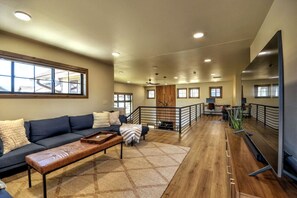 A spacious living area with a dark blue sofa, a wooden coffee table, and a patterned rug. There is a staircase leading to an upper level with a railing. - Private sauna, close to ski mountain and downtown (Red Lodge)