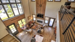 A spacious living area with a fireplace, large windows, and a staircase leading to an upper level. - Private sauna, close to ski mountain and downtown (Red Lodge)