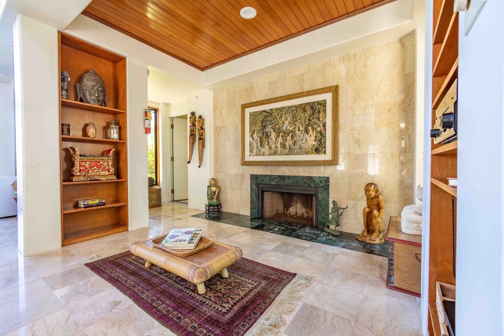 A spacious living room with a fireplace, a wooden bookshelf, and a large painting on the wall.
