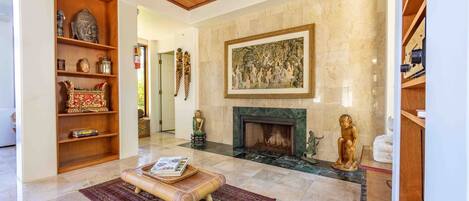 A spacious living room with a fireplace, a wooden bookshelf, and a large painting on the wall.