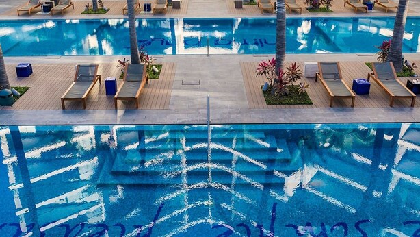 A large outdoor swimming pool with multiple lounge areas and palm trees. - Luxury Waterfront 2BR Condo w/ Pool, Gym & Bar, Puerto Vallarta (Puerto Vallarta)