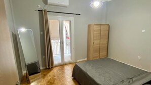 A bedroom with a bed, a wardrobe, a mirror, and a ceiling light. - Sweety flat Marina Zeas Piraeus nearby the sea (Pireas)