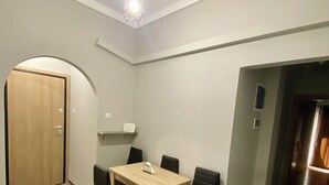 A dining area with a wooden table and black chairs, a wooden door, and a ceiling light fixture. - Sweety flat Marina Zeas Piraeus nearby the sea (Pireas)