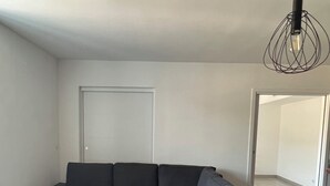 A modern living room with a sectional sofa and a small ottoman. - Cozy 3-bedroom apartment with WiFi, AC in amazing Bonifacio (Bonifacio)