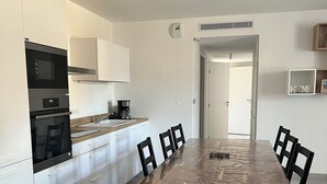 A modern kitchen with built-in appliances, a dining table with chairs, and a hallway leading to another room. - Cozy 3-bedroom apartment with WiFi, AC in amazing Bonifacio (Bonifacio)
