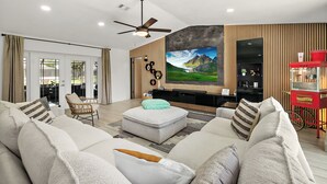 Una sala de estar moderna con un televisor de pantalla plana grande, asientos cómodos y una máquina para hacer palomitas de maíz.