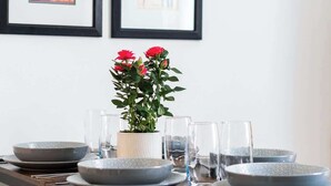 Ein Esstisch mit Geschirr, Gläsern und einer Blumentopf-Pflanze.