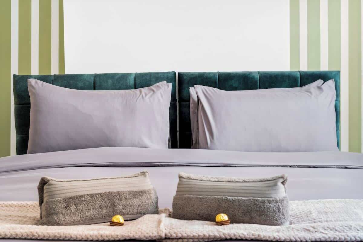 A bed with two pillows, a blanket, and two small pillows on a bed.