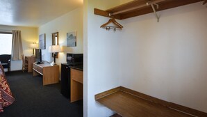 Habitació d'hotel amb llit, escriptori, cadira, televisió i prestatge de fusta.