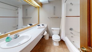 A modern bathroom with a white sink, mirror, and toilet. There is a shower area with a glass door and a bathtub. - Hearthstone Lodge #327 (Sun Peaks)