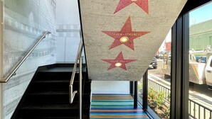 A staircase with a colorful striped floor and three stars with names on the wall. - Hotel Rudra - Hollywood (Los Angeles)