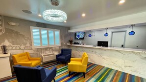 A hotel reception area with a marble counter, a large chandelier, and a colorful striped carpet. - Hotel Rudra - Hollywood (Los Angeles)