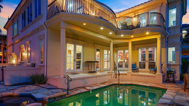 Ein großes Haus mit Schwimmbad, überdachter Terrasse und Balkon mit Geländer.