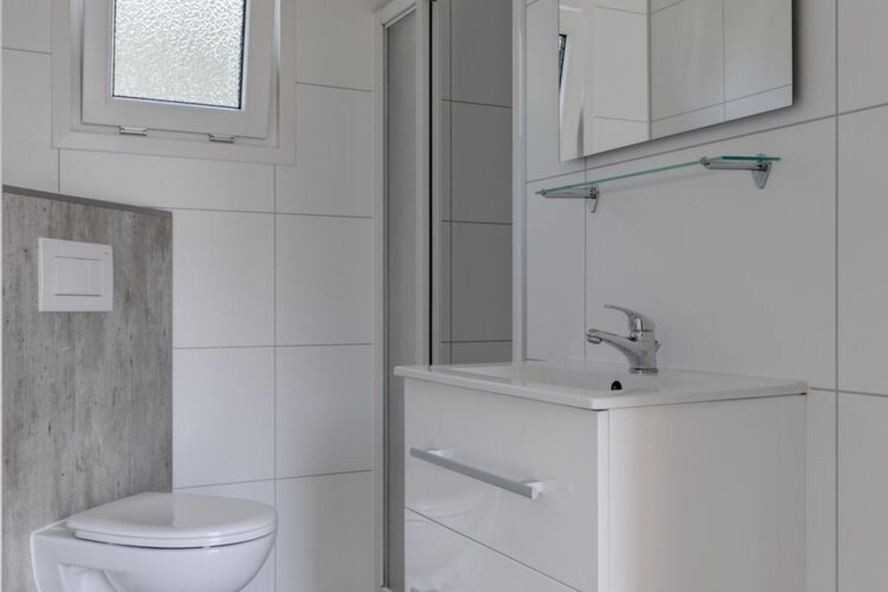 Et moderne badeværelse med toilet, vask og spejl.