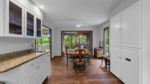 A kitchen with white cabinets, a granite countertop, and a dining area with a wooden table and chairs.