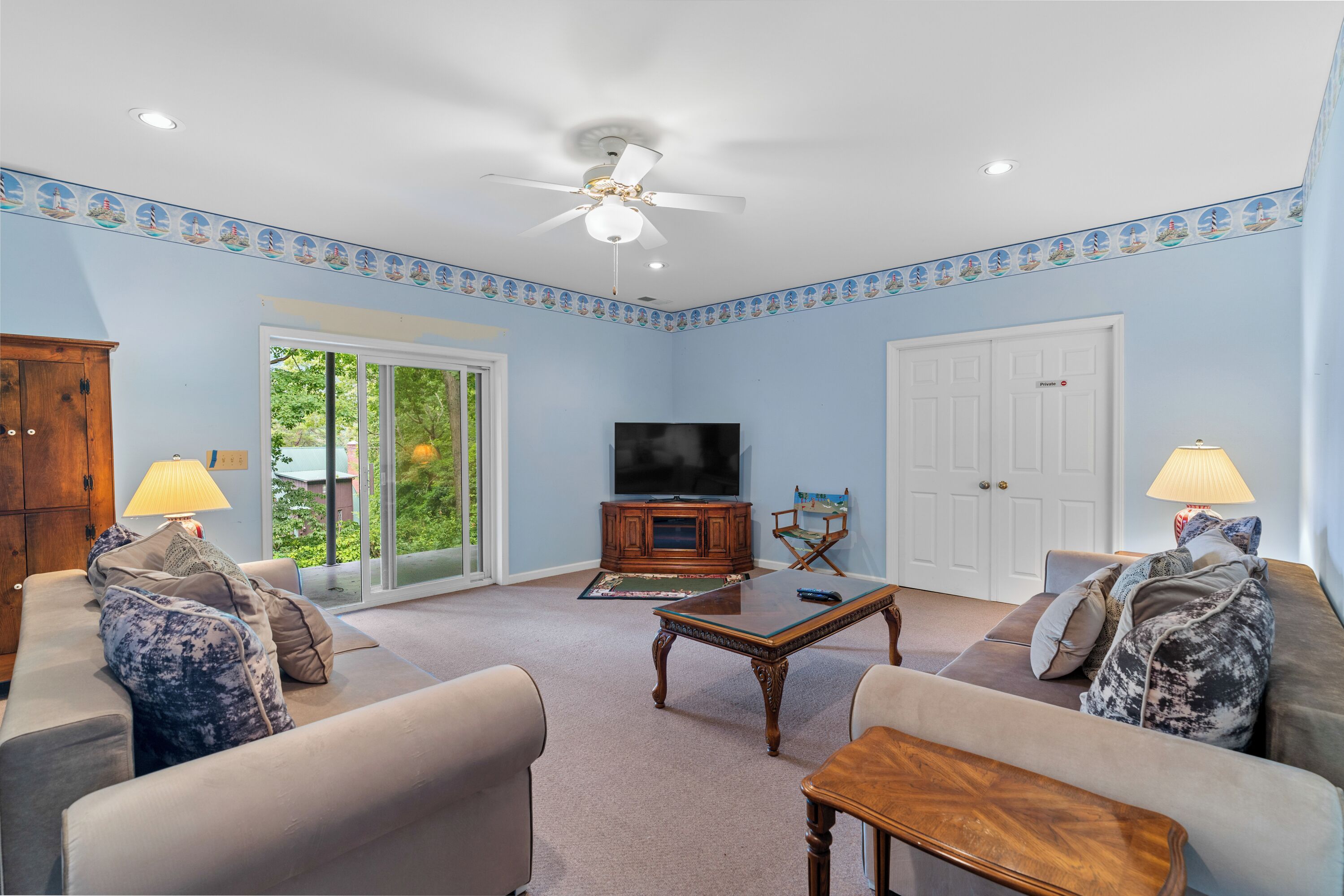 A living room with a ceiling fan, a television, and two sofas with patterned cushions.
