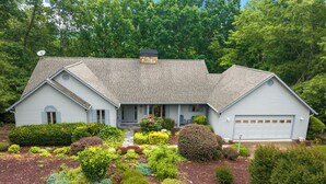 A two-story house with a garage, surrounded by a landscaped garden with various shrubs and a stone pathway.