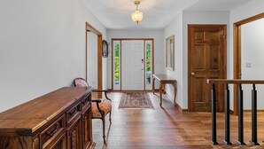 A hallway with a wooden bench, a rug, and a staircase with black balusters.