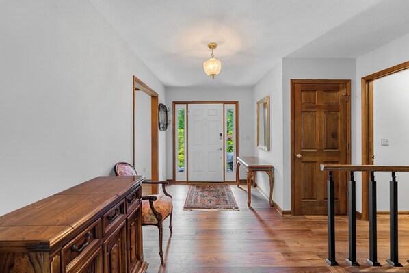 A hallway with a wooden bench, a rug, and a staircase with black balusters.