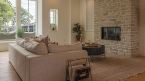 A living room with a stone fireplace, a sofa, and a large window.