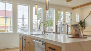 A modern kitchen with large windows, a central island, and a view of the outside.
