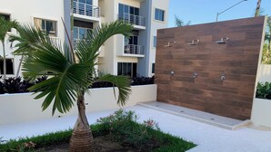 Un bâtiment moderne avec une façade en bois, un palmier et un petit espace jardin.