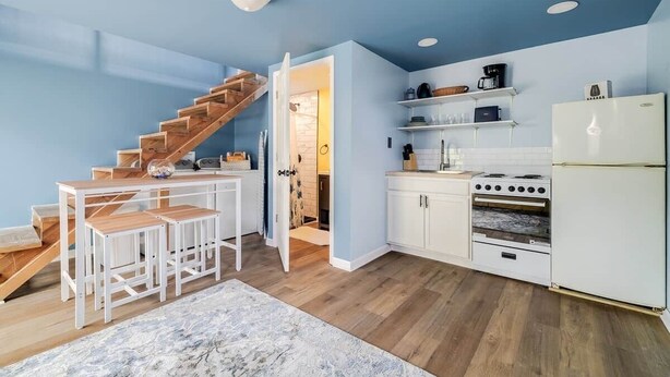 A compact kitchen with white cabinets, a built-in oven, and a white refrigerator. - Tiny House 20 Mins from Beach (Brunswick)
