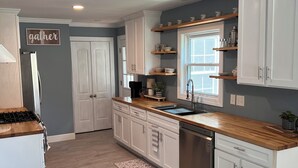 A modern kitchen with white cabinetry, a wooden countertop, a built-in dishwasher, and a window above the sink. - The Cardinals Nest, Charming 4-bedroom house, Historic Village of Ballston Spa.  (Ballston Spa)