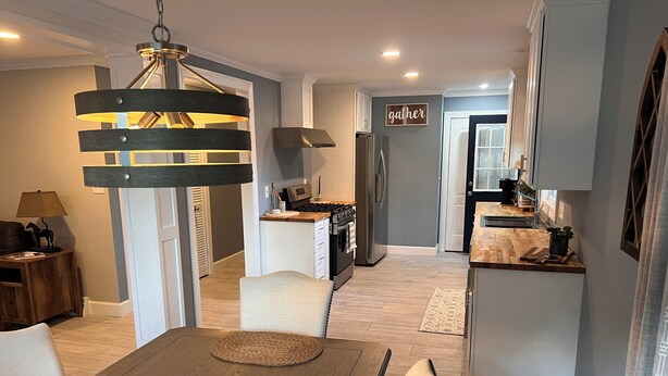 A modern kitchen with a central island, a dining area with a wooden table and woven placemats, and a sign that reads "gather" on the wall. - The Cardinals Nest, Charming 4-bedroom house, Historic Village of Ballston Spa.  (Ballston Spa)