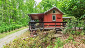 Eine rote Holzhütte mit Veranda, umgeben von dichtem Wald.