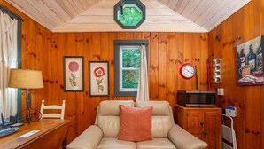 Ein gemütliches Zimmer mit Holzvertäfelung, einer Ledersofa, einem Esstisch, einer Uhr und einem Fenster mit Vorhängen.