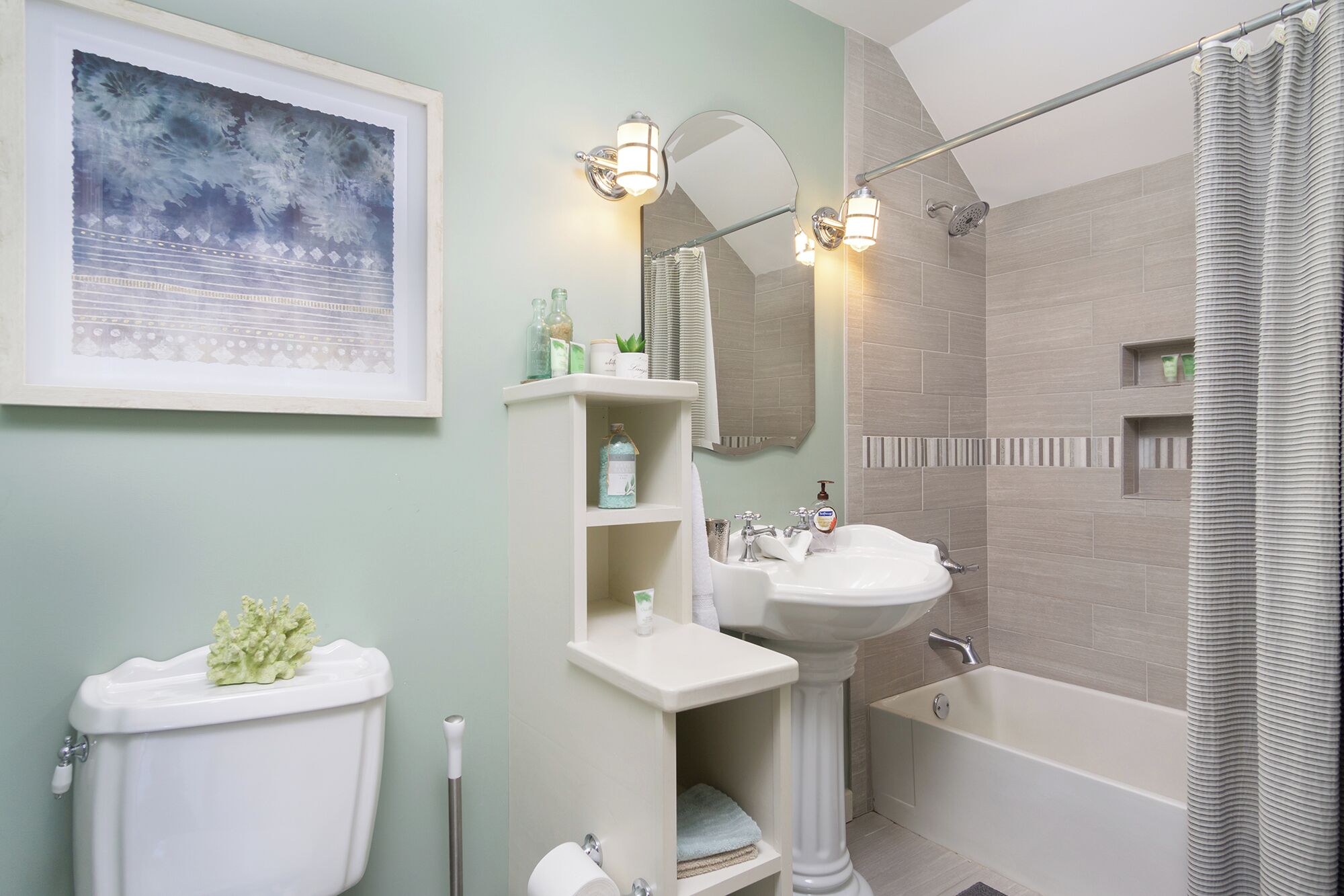 A bathroom with a toilet, pedestal sink, bathtub, and shower curtain.