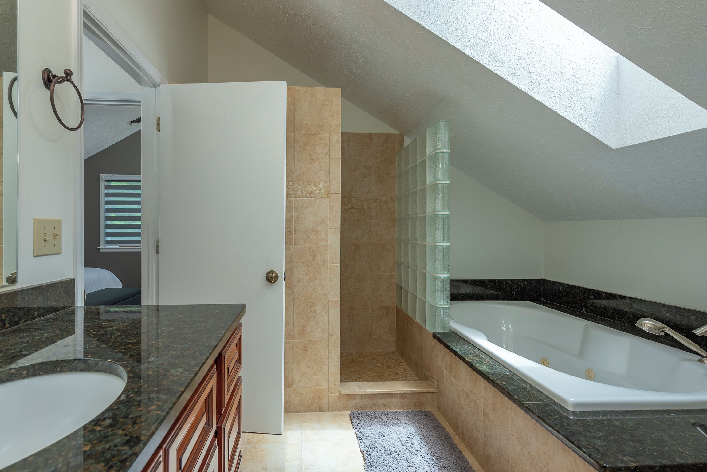 Uma casa de banho moderna com uma banheira grande, um chuveiro amplo e uma toucador com bancada de granito.