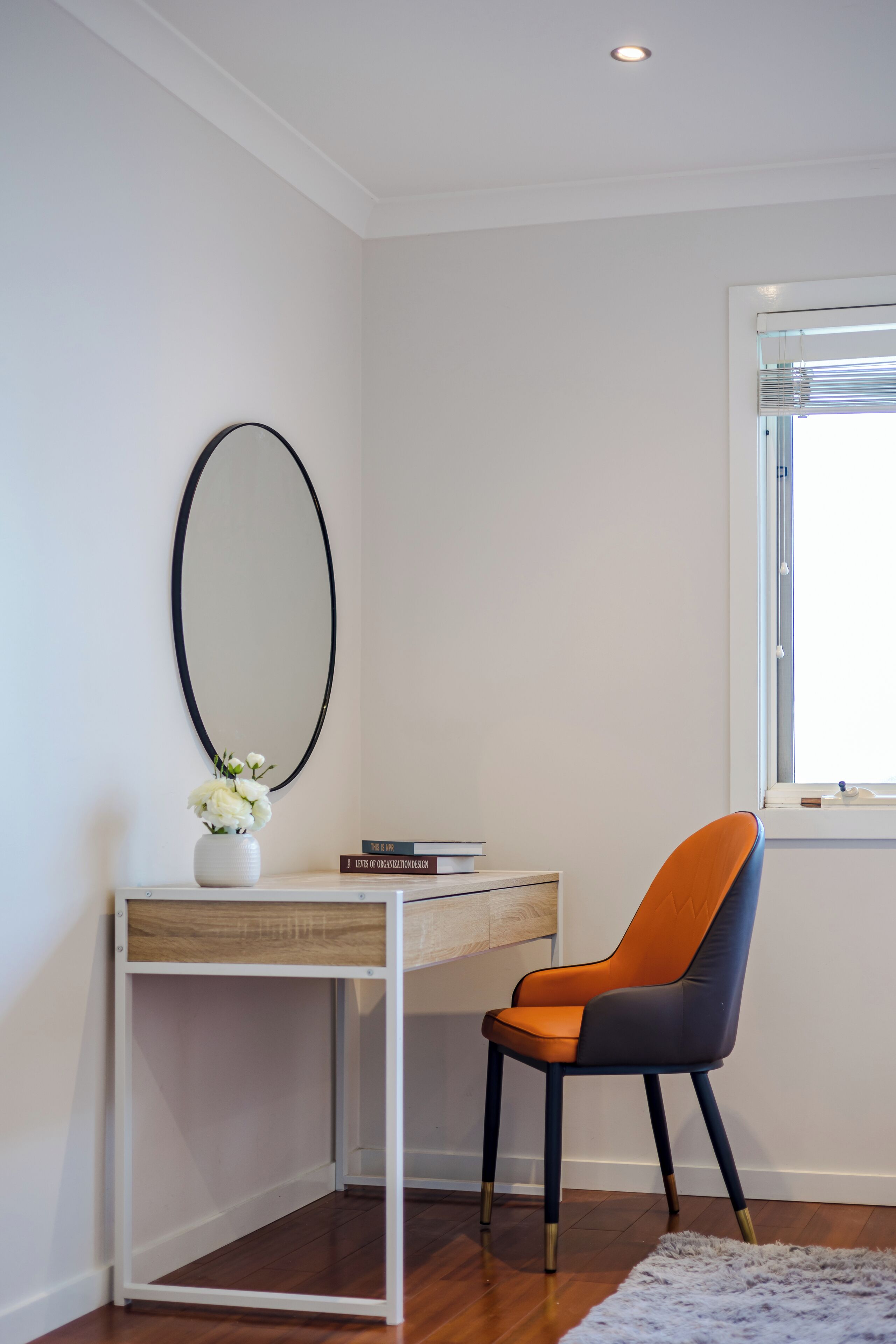 Habitación de esquina con escritorio, silla y ventana.
