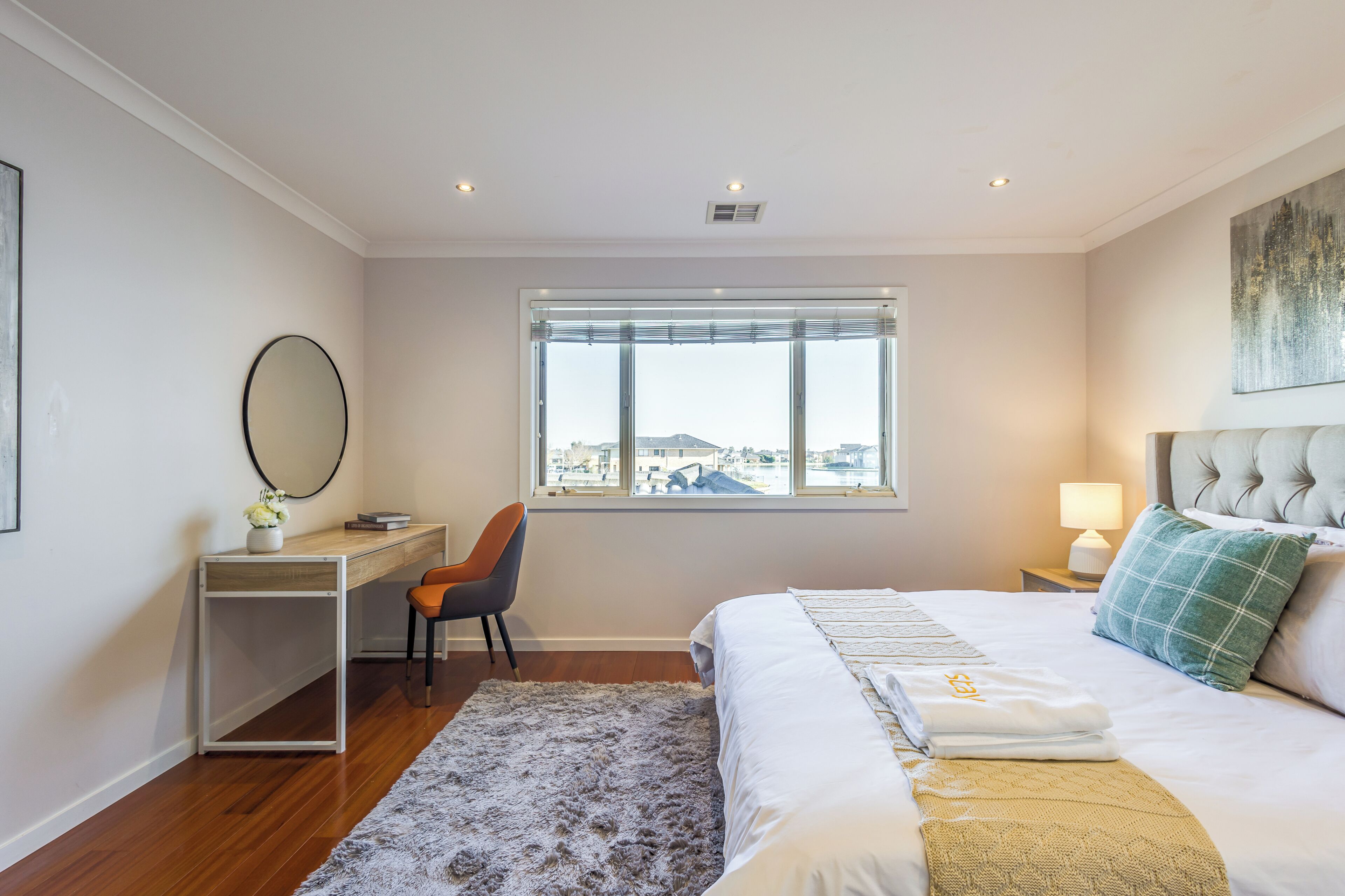 Une chambre à coucher comprenant un lit, un bureau, une chaise, une fenêtre avec vue et une lampe de chevet.