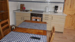 Une cuisine de taille réduite avec une table en bois, une nappe à carreaux et des appareils électroménagers de base.