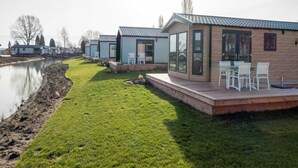 Acomodação moderna em estilo de motorhome, com um gramado, um pequeno deck e vista para um rio.